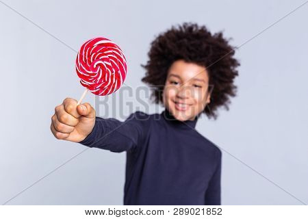 Resolute Dark-haired Joyful Boy Pulling Out Hand With Candy In It