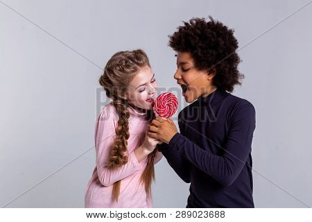 Active Beaming Opposite Kids Biting One Candy Together