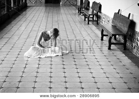 Giovane donna in abito bianco sul pavimento