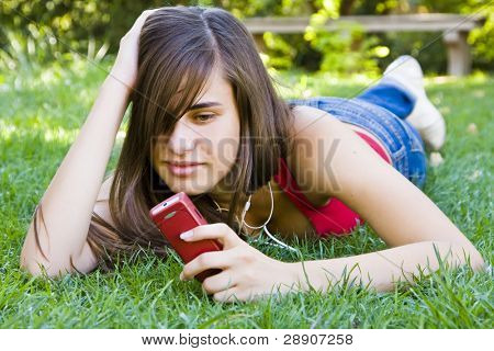 彼女の電話を使用して、公園で若い女性。