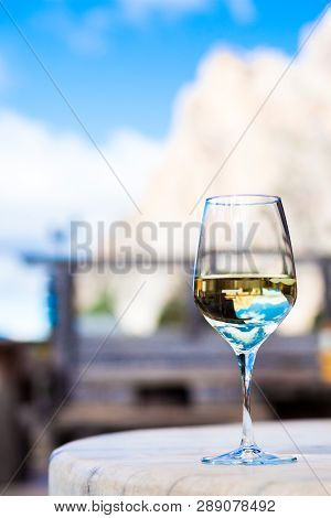 Glass Of Chilled White Wine On A Rocky Mountain Background. Hiking In Dolomites, Italy