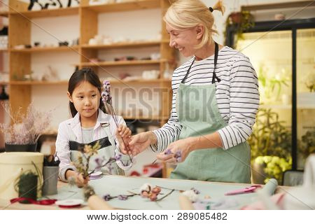 Portrait Of Smiling Mature Woman Creating Flower Compositions With Little Asian Girl, Copy Space
