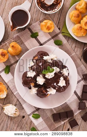 Chocolate Profiteroles With Whipped Cream On White Dish.