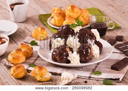 Chocolate Profiteroles With Whipped Cream On White Dish.