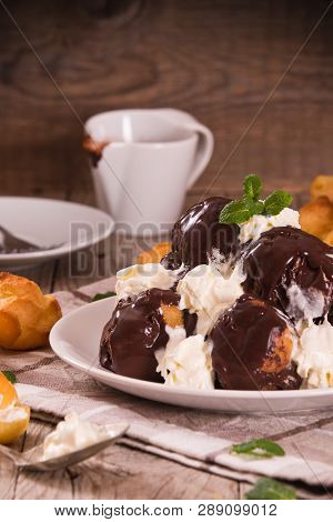 Chocolate Profiteroles With Whipped Cream On White Dish.