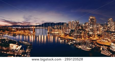 Vancouver harbor view with urban apartment buildings and bay boat at dusk in Canada.