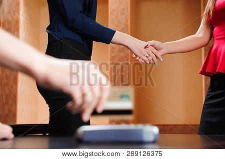 Hand Swiping Debit Card On Pos Terminal, Business People In Office Holding A Conference And Discussi