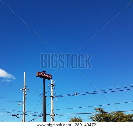 Blue Sky With Cables And Sign Saying Desayuno In Spanish Or Breakfast