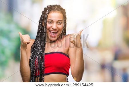 Young braided hair african american with pigmentation blemish birth mark over isolated background success sign doing positive gesture with hand, thumbs up smiling and happy. Looking at the camera
