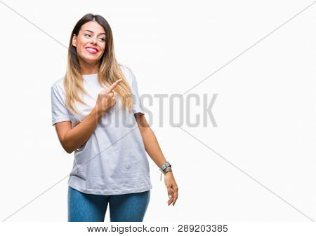 Young beautiful woman casual white t-shirt over isolated background cheerful with a smile of face pointing with hand and finger up to the side with happy and natural expression on face