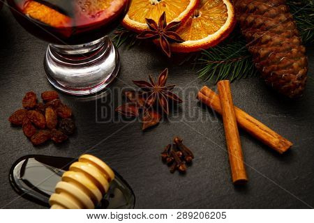 Homemade Mulled Recipe With Cinnamon, Star Anise, Dried Orange, Honey, Cloves, Raisins Over A Black 