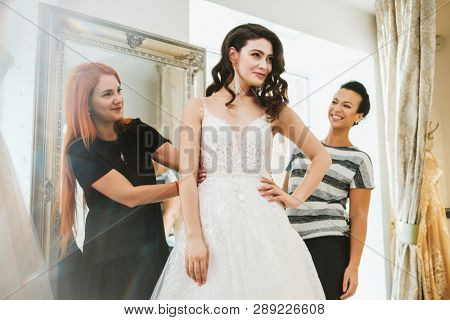 Beautiful bride choosing wedding dress in a wedding salon
