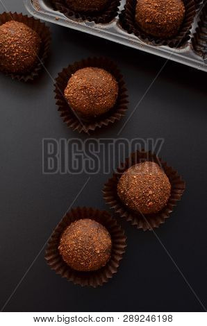 Chocolate Petit Fours Over Black Background. Top View.