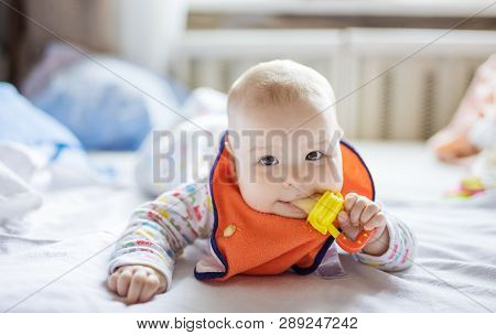 Cute Little Baby Eating Fruit In Nibbler On Bed At Home