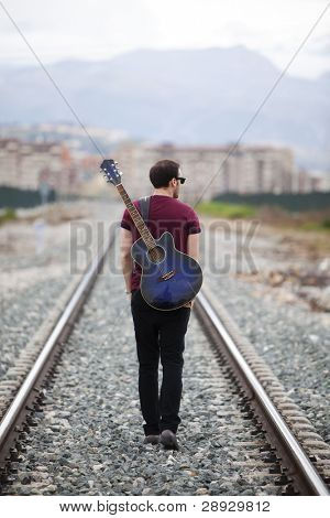 Ung mandlig musiker gå med sin akustiske guitar.