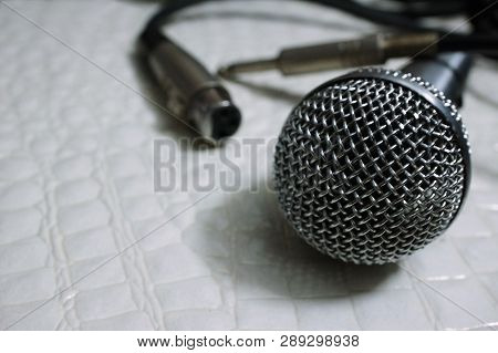 Silver Grille Microphone With Xlr Cable On White Leather Selective Focus
