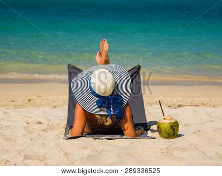 Woman with straw hat enjoying her holidays on a transat at the tropical beach in Thailand