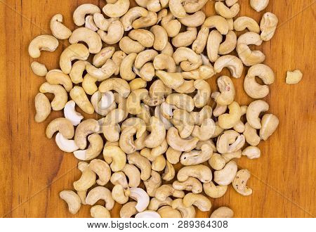 Cashew Nuts On Wooden Background, Top View Photo. Tasty Healthy Snack. Scattered Nut On Table. Organ
