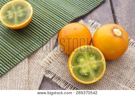 Fruits And Slices Of Lulo Or Naranjilla On The Wooden Table - Solanum Quitoense