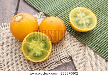 Fruits And Slices Of Lulo Or Naranjilla On The Wooden Table - Solanum Quitoense