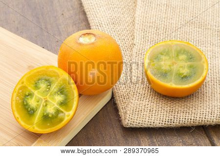 Fruits And Slices Of Lulo Or Naranjilla On The Wooden Table - Solanum Quitoense