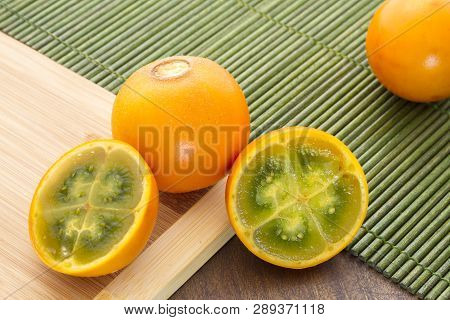 Fruits And Slices Of Lulo Or Naranjilla On The Wooden Table - Solanum Quitoense