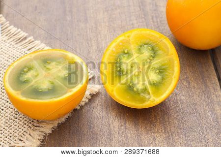 Fruits And Slices Of Lulo Or Naranjilla On The Wooden Table - Solanum Quitoense