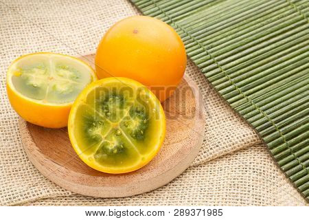 Fruits And Slices Of Lulo Or Naranjilla On The Wooden Table - Solanum Quitoense