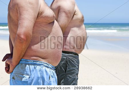 해변에서 그들의 배를 보여주는 두 뚱뚱한 남자의 마지막