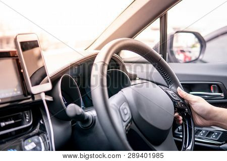 Male Driver Hand Holding On Steering Wheel Using Smartphone For Gps Navigation. Mobile Phone Mountin
