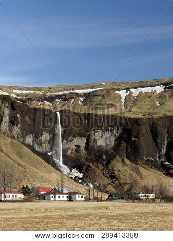 Basalt Cliff, Foss A Sidu Waterfall And Farm, With Blue Sky In Winter Seen From Road 1, Southern Ice