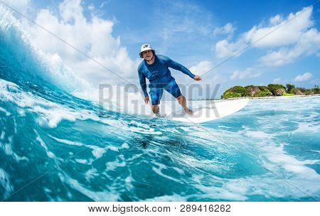 MALDIVES / HIMMAFUSHI - 10 MARCH 2019: Male surfer rides the torquoise ocean wave