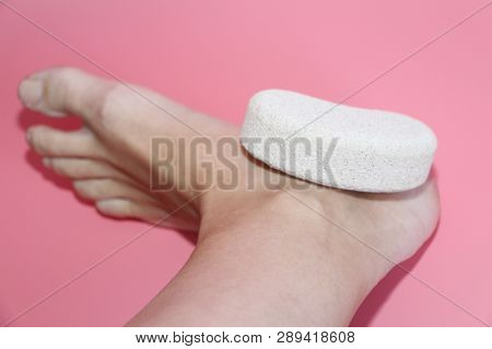 Pumice Stone For Foot Care. In The Photo A Woman Hand Holds A Pumice Near The Heel Of Her Foot. Remo
