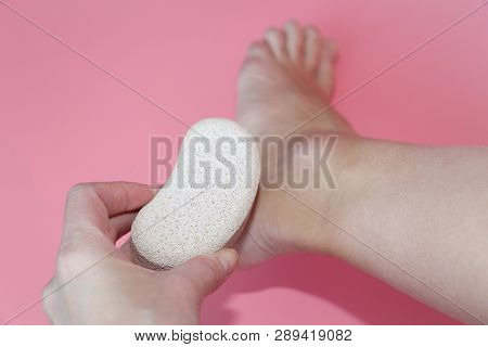 Pumice Stone For Foot Care. In The Photo A Woman Hand Holds A Pumice Near The Heel Of Her Foot. Remo