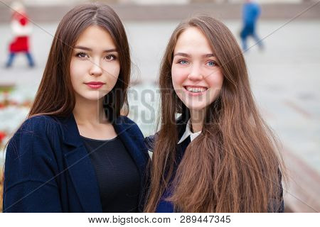 Two happy young women walking in autumn park, outdoors