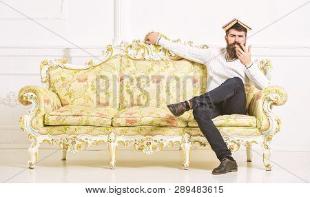 Macho Sits With Open Book On Head, Like Roof. Overstudy Concept. Man With Beard And Mustache Sits On