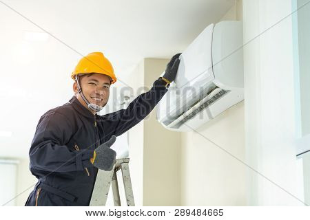 Male Technician Repairing Air Conditioner Safety Uniform Indoors.