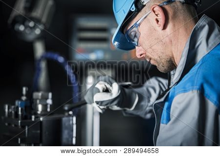 Metalworking Technician At Work. Caucasian Factory Worker In Blue Hard Hat And Safety Glasses.