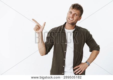 Pleasant And Charismatic Blond Boyfriend Pointing Left As Showing Around New Apratment Smiling Frien
