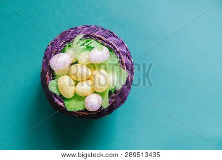 Easter Composition With Traditional Decor. Small Colorful Eggs And Feathers In Wicker Basket On Soft