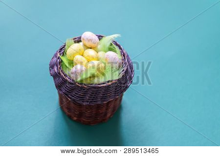 Easter Composition With Traditional Decor. Small Colorful Eggs And Feathers In Wicker Basket On Soft