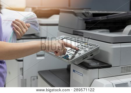 Bussinesswoman Using Copier Machine To Copy Heap Of Paperwork In Office.