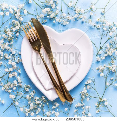 Plates In Form Of Hearts, Golden Knife And Fork And  Fresh White Gypsofila  Flowers On Blue Textured