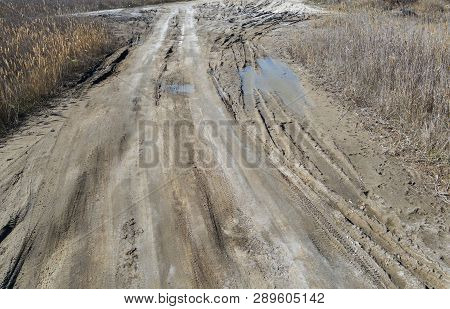 Off-piste. Deep Rubber Tracks On The Road Is Covered With Wet Dirty Sand, Off-road. Traces Of Tires