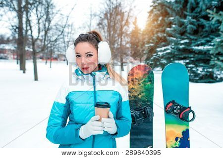 Beautiful Girl In Winter Forest, Snowboard Boards Background Snow Drifts Green Christmas Trees. In H