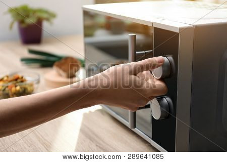 Young Woman Adjusting Modern Microwave Oven In Kitchen, Closeup