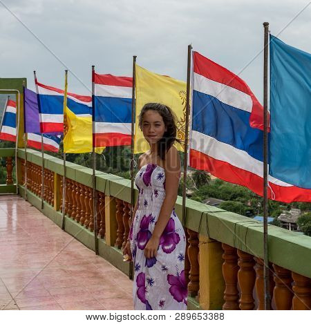 Young Girl Standing In Front Of Row Of Flags At Wat Tham Suea