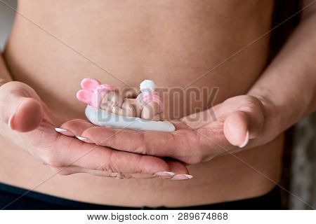 Pregnant Young Woomen Holds A Figurine Of Soap In The Shape Of A Newborn Baby Girl In Front Of Her B