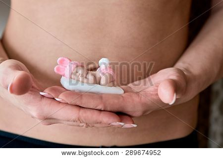 Pregnant Young Woomen Holds A Figurine Of Soap In The Shape Of A Newborn Baby Girl In Front Of Her B