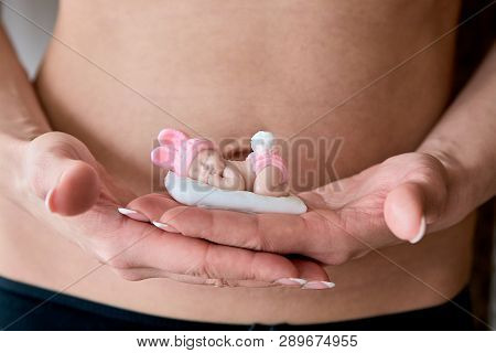 Pregnant Young Woomen Holds A Figurine Of Soap In The Shape Of A Newborn Baby Girl In Front Of Her B